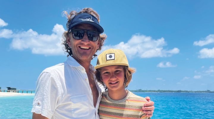 Two people smiling in front of a bright blue ocean